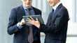 © Trickster* - タブレットを見ながら話す2人の男性ビジネスマン, Two Businessmen Discussing While Looking at a Tablet