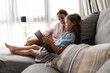 © AresStudio Belen y Carlos/Stocksy - Mother and daughter reading book together on sofa