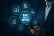 © Tanu - A businessman examines a digital sales report display with charts and data visualization