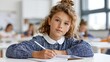 © inspiretta - Young girl writes in notebook at school desk.