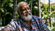 © Olga Ко - Retrato de um homem idoso afro-brasileiro sorrindo e relaxando em um parque ensolarado. Conceito de aposentadoria feliz e envelhecimento saudável