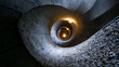 © Nick Freund - Spiralförmige Betontreppe von oben mit Lichtpunkt in der Tiefe