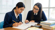 © tu - Diligent teenage schoolgirl in formal academy uniform engaged in private academic tutoring session with mentor at wooden desk within bright classroom environment for educational excellence.