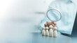 © Garun Studios - HR professional using a magnifying glass to evaluate candidates represented by wooden figures, illustrating recruitment, talent acquisition, employee screening, and workforce selection.