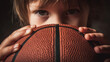 © Darya - Child holds basketball close while looking directly at the viewer in a simple indoor setting