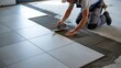 © PAVEL - The hands of the tiler are laying the ceramic tile on the floor. Close up macro shot. Home renovation and building new house concept