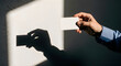 © SHAKIBULHASSAN - Hand holding blank white business card with dramatic shadow on wall