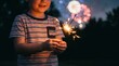 © RyuRyu - Young boy holding a burning sparkler with festive fireworks background during night celebration