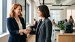 © Eve - Two diverse smiling businesswomen handshake in modern office, successful partnership agreement, corporate hiring, collaboration team building
