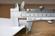 © Fotograf - A close-up view of a caliper measuring a piece of paper, suitable for use in educational or scientific contexts