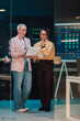 © Zamrznuti tonovi - Female it professionals collaborating in a data center, analyzing information on a clipboard with network racks and monitoring screens