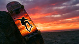 Silhouette of a Skateboarder Performing a Trick Against a Dramatic Sunset Sky on a Beach