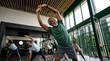 © Milan - Smiling senior Black man doing stretching exercises in a group fitness class. Older adults working out together in a modern gym. Active aging and community wellness concept