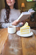 © Farknot Architect - Vertical closeup image of a woman reading a book with coffee cup and a lemon cake on the table