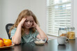 © Volodymyr - Kid showing loss of appetite. Child with poor appetite indoors. Kid not eating breakfast. Child pushing plate away. Kid struggling with appetite. Child refusing healthy food. Kid with eating problem.