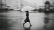 © jodoto - A solitary figure with an umbrella walking through the rainy city, captured in a moody black and white atmosphere
