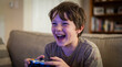 © Jian - Video Game Day celebration with happy boy playing console games laughing joyfully at home for entertainment technology youth culture gaming lifestyle content