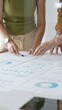 © rogerphoto - Business professionals analyzing financial reports, pointing at charts during collaborative meeting, discussing data with focused professional demeanor