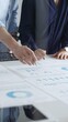 © rogerphoto - Business colleagues are examining financial data, pointing at charts and graphs spread out on a table during a collaborative analysis session in a modern office.