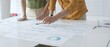 © rogerphoto - Business professionals analyzing financial reports, pointing at data points on charts and graphs lying across white desk surface