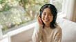 © AoIro scIA - 明るいリビングのソファでヘッドホンで音楽を聴いて笑顔を見せる若い女性、おうち時間やリラックスしたライフスタイルをイメージしたポートレート写真素材