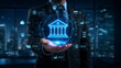 © Vactzone - Fintech innovation and digital banking security concept. Businessman holding glowing bank interface with circuit board and financial icons for secure online investment