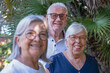 © luciano - Smiling senior friends enjoying retirement and happy summer vacation, spending leisure time together in an outdoor setting with green palm trees