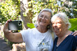 © luciano - Two happy senior women taking a selfie outdoors, smiling and enjoying friendship and retirement together during a sunny day in a park