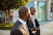 © Marko Geber - Two business professionals talking while walking outside an office building