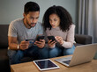 © SuperImages - Worried couple looking at phone screens at home