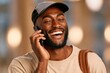 © Georgii - Happy young man with beard talking on phone while wearing a cap and carrying a backpack