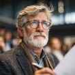 © Mikhail Vorobev - Thoughtful mature man with gray beard and glasses attentively listening and taking notes during a professional conference or seminar indoors
