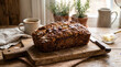 © Cascade Image Studio - Steaming whole rustic banana bread with a rich, textured crust resting on natural cutting board with a softly blurred background