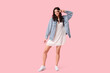 © Pixel-Shot - Beautiful young woman in stylish white dress dancing and showing victory gesture on pink background