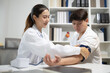 © Somdetmeaow - Doctor records patient's blood pressure reading. Patient rests arm with cuff securely fitted. Clinic setting suggests routine health monitoring. Professional demeanor shows care and precision