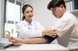 © Somdetmeaow - Doctor records patient's blood pressure reading. Patient rests arm with cuff securely fitted. Clinic setting suggests routine health monitoring. Professional demeanor shows care and precision