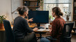 © Mehedi - An experienced mentor and young colleague sit side by side at a desk studying a monitor together, perfect for coaching and knowledge-transfer business concepts.