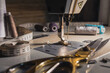 © Владимир Трубачёв - Close-up of a sewing machine with thread, measuring tape, scissors and sewing tools on a worktable. Tailoring, garment making and textile craft concept.