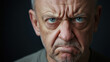 © Keopaserth - Angry man portrait intense face furrowed brow stern expression blue eye bald head close up dark background facial wrinkle older adult
