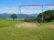 © minako - Swing Set on Grassy Hill with Mountain View