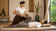 © Phonlasit - Thai Massage Therapist Stretching Client Leg on Massage Mat