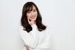 © Jumpei - 白いセーターを着た笑顔の若い日本人女性が頬に指を当てる
