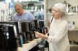 © JackF - Undecided elderly woman choosing air fryer while shopping inside at household appliances store