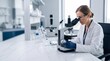 © AdPremium - Professional female scientist in a white lab coat and safety goggles conducting research using a modern microscope in a bright clinical laboratory