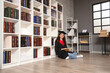 © Pixel-Shot - Female graduating student reading book on floor in library