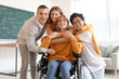 © Pixel-Shot - Group of teenage students with girl in wheelchair hugging at school