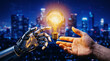 © Gilang - Robot hand offering a glowing light bulb with a brain inside to a human hand, symbolizing artificial intelligence and innovation.