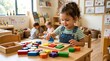 © Noyon - Happy little girl playing with colorful wooden shape sorter puzzle in a preschool classroom
