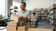 © Suvro - Warehouse worker smiling while holding a cardboard delivery box inside a logistics distribution center.