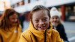 © Studio Zenith - Enfant trisomique souriant en veste jaune entouré de camarades